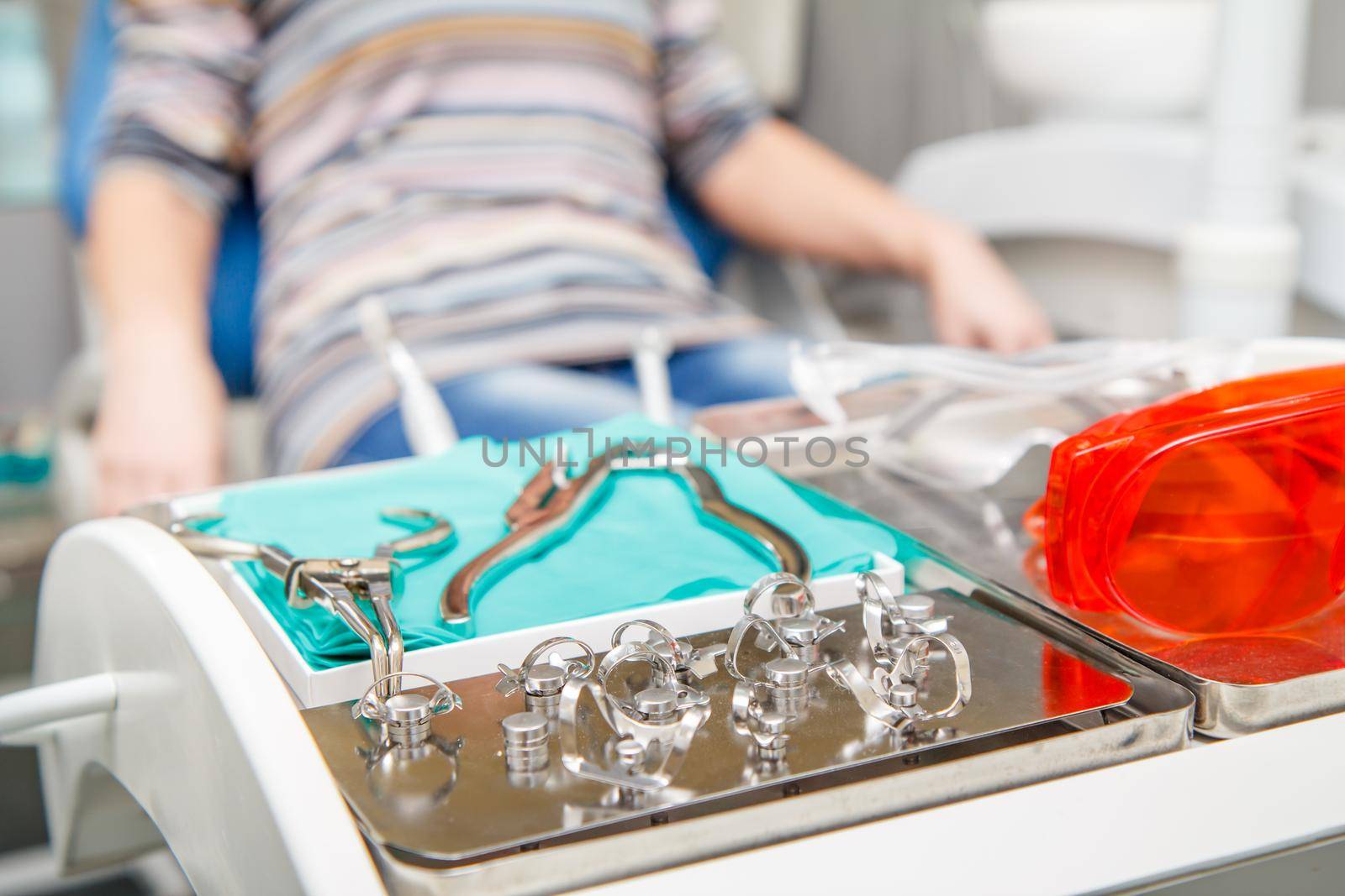 Dental instruments on stainless steel tray are prepared for the dental treatment of patient in dental clinic. Professional tools for dentists. Shallow depth of field, focus on instruments.