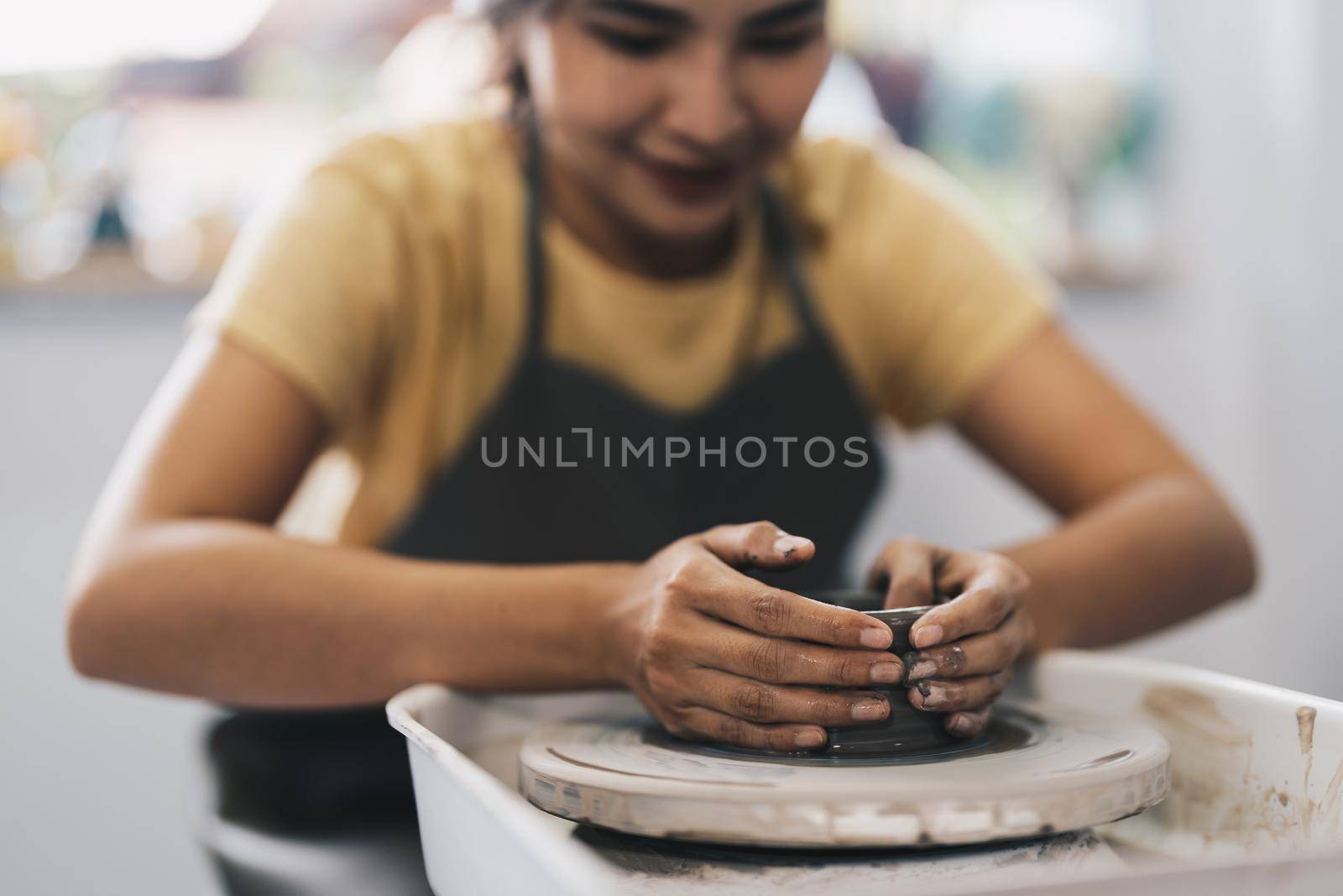 Woman working on the potter's wheel. Artisan making a cup from clay pot. Workshop of handmade modeling on the potters wheel