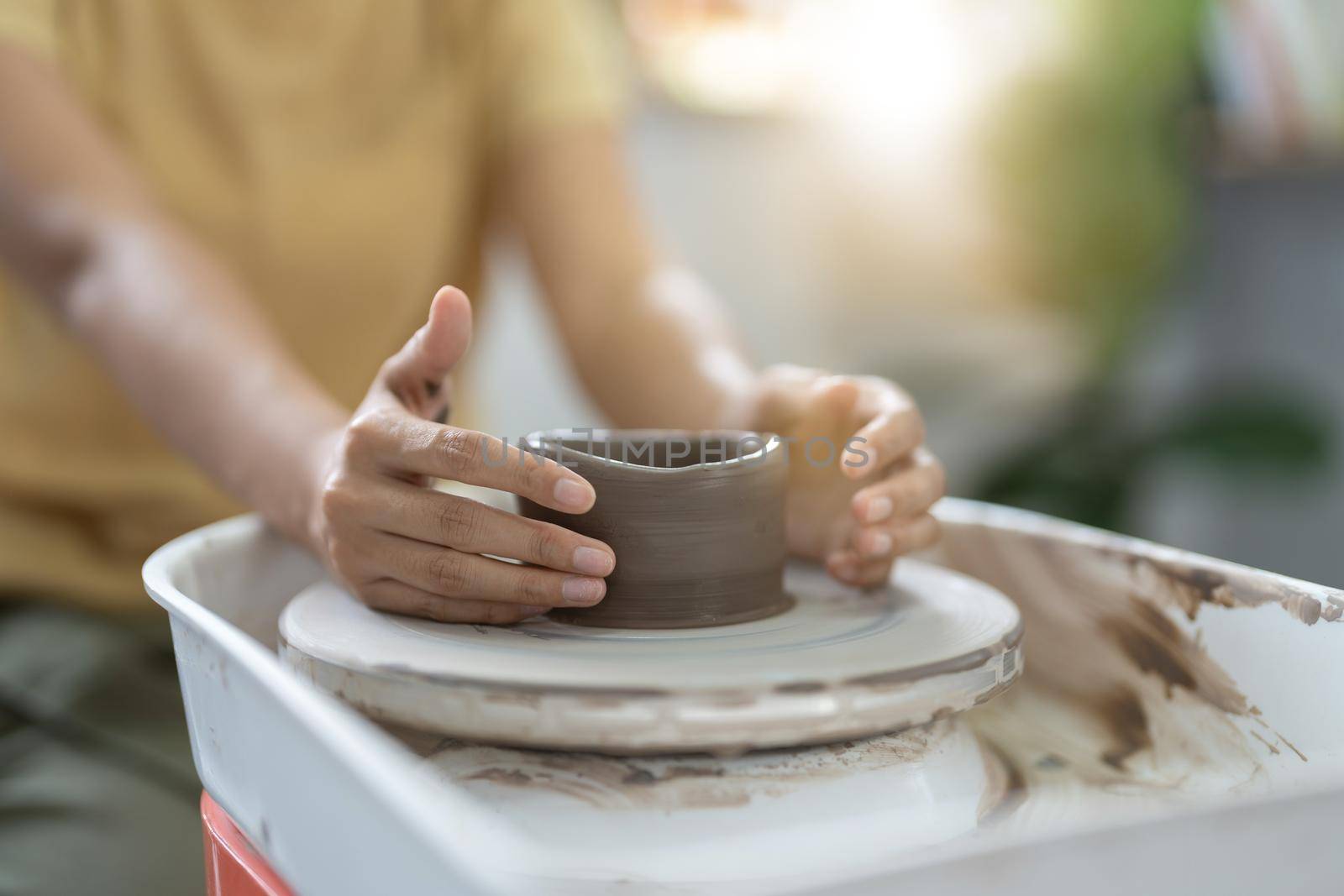 Craftsman hands making pottery bowl. Woman working on potter wheel. Family business shop sculpts pot from clay