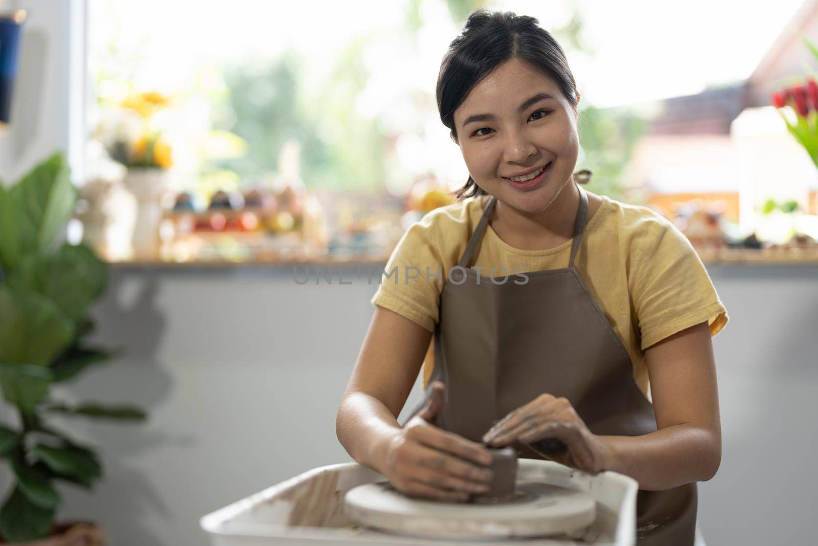 Young asian woman's hands close up, the masterful studio of ceramics works with clay on a potter's wheel