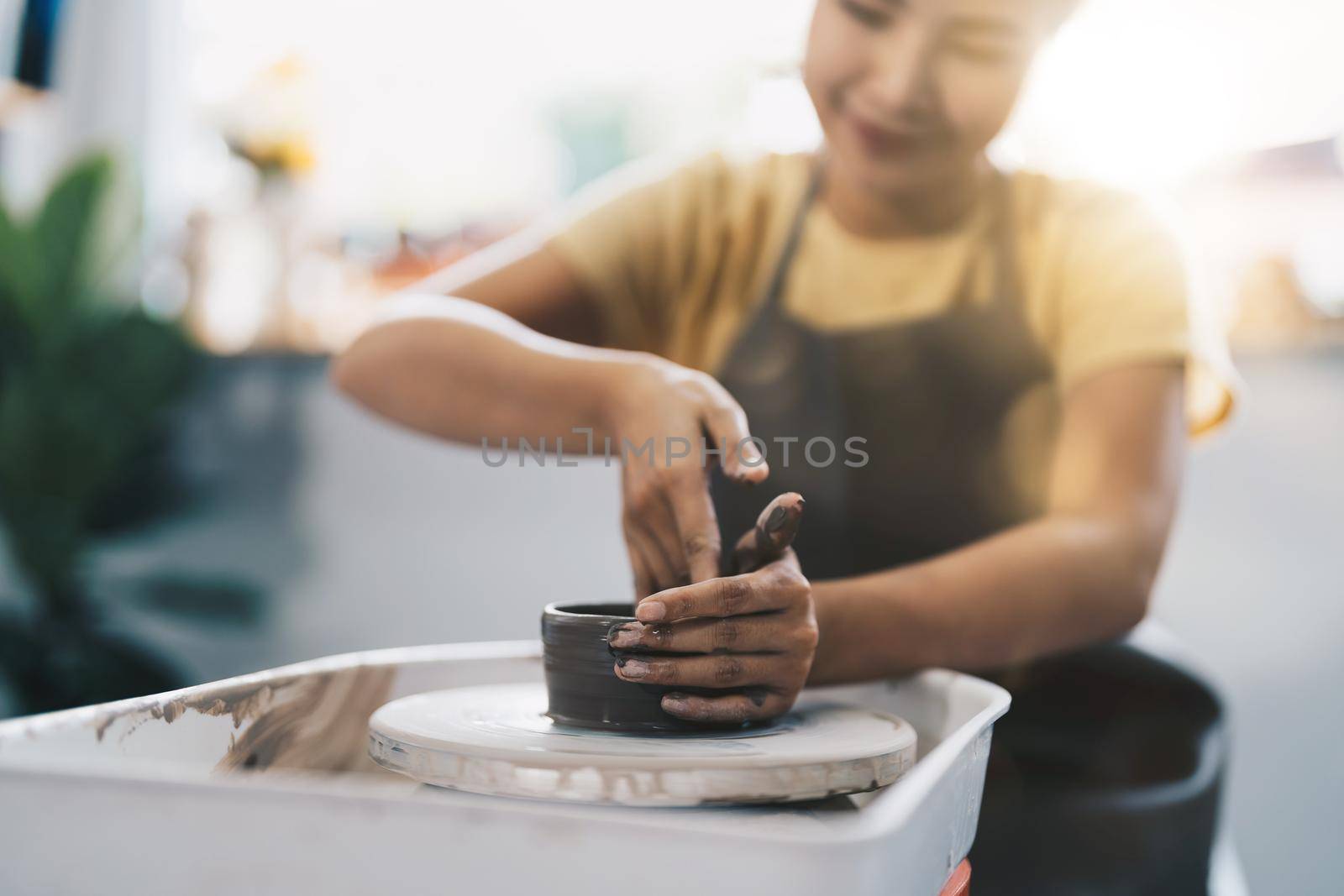 Woman working on the potter's wheel. Artisan making a cup from clay pot. Workshop of handmade modeling on the potters wheel