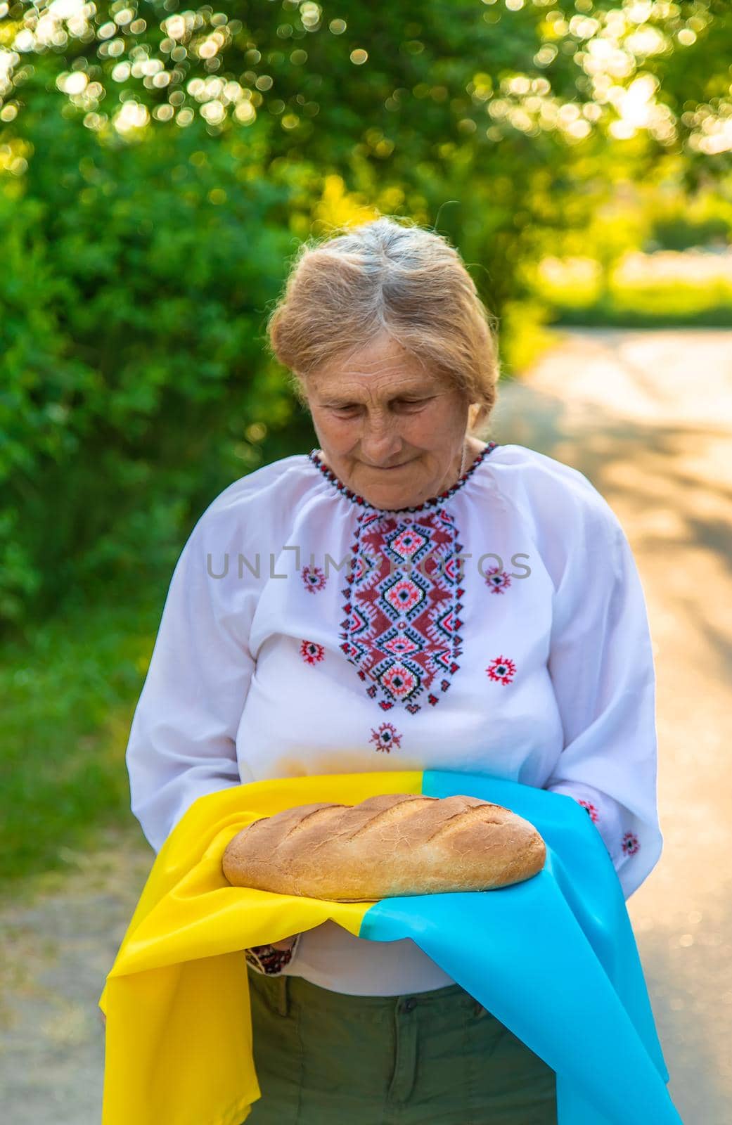 Grandmother with Ukrainian bread in her hands. Selective focus. Food.