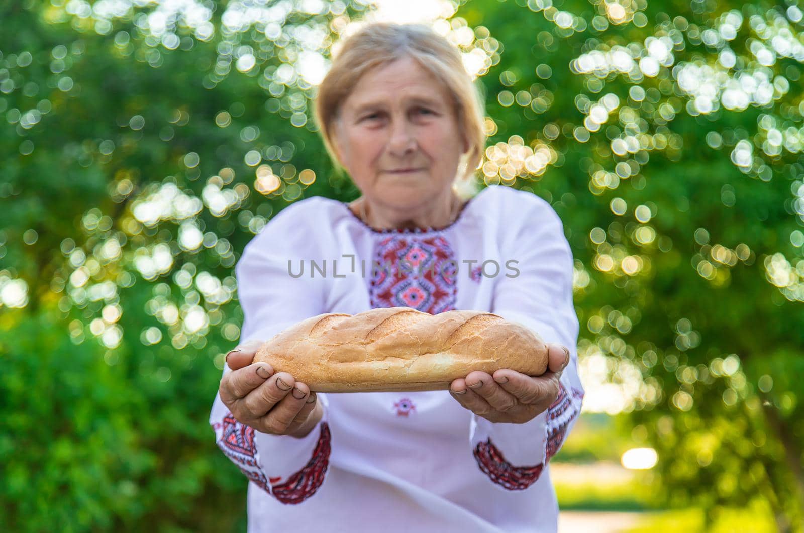 Grandmother with Ukrainian bread in her hands. Selective focus. Food.