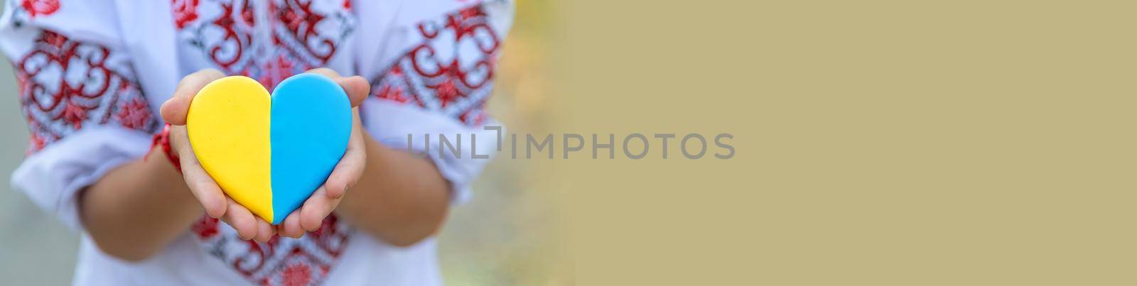 A child holds a heart of the Ukrainian flag. Selective focus. People.