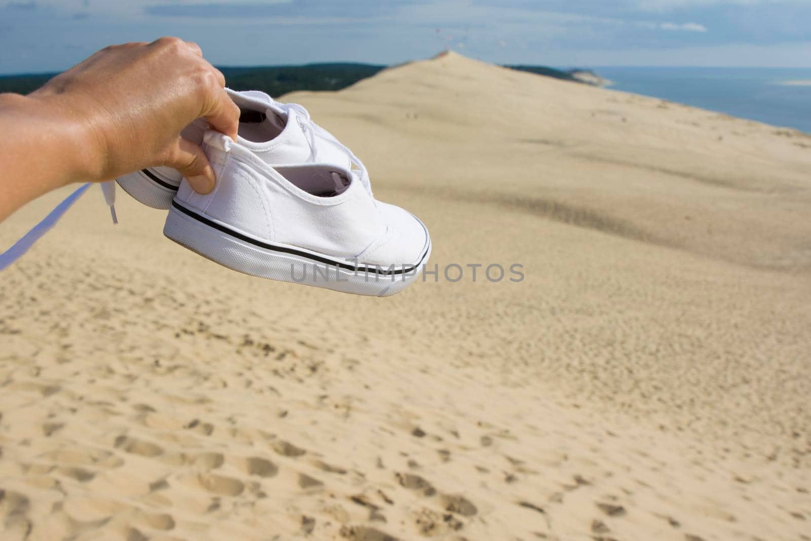White traveler's sneakers on the background of Pilat dune, the largest sand dune in Europe, France