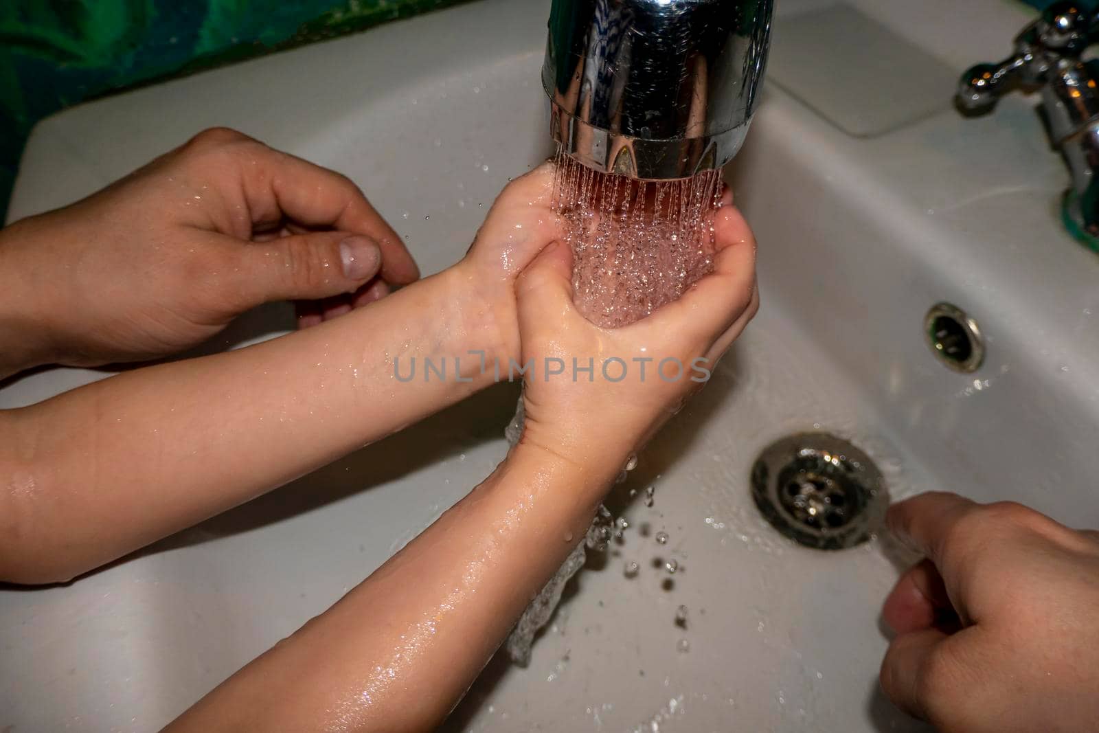 Close up of caucasian man and child together washes his hands in the bathroom. COVID - 19 prevention. water jet games, care. High quality photo