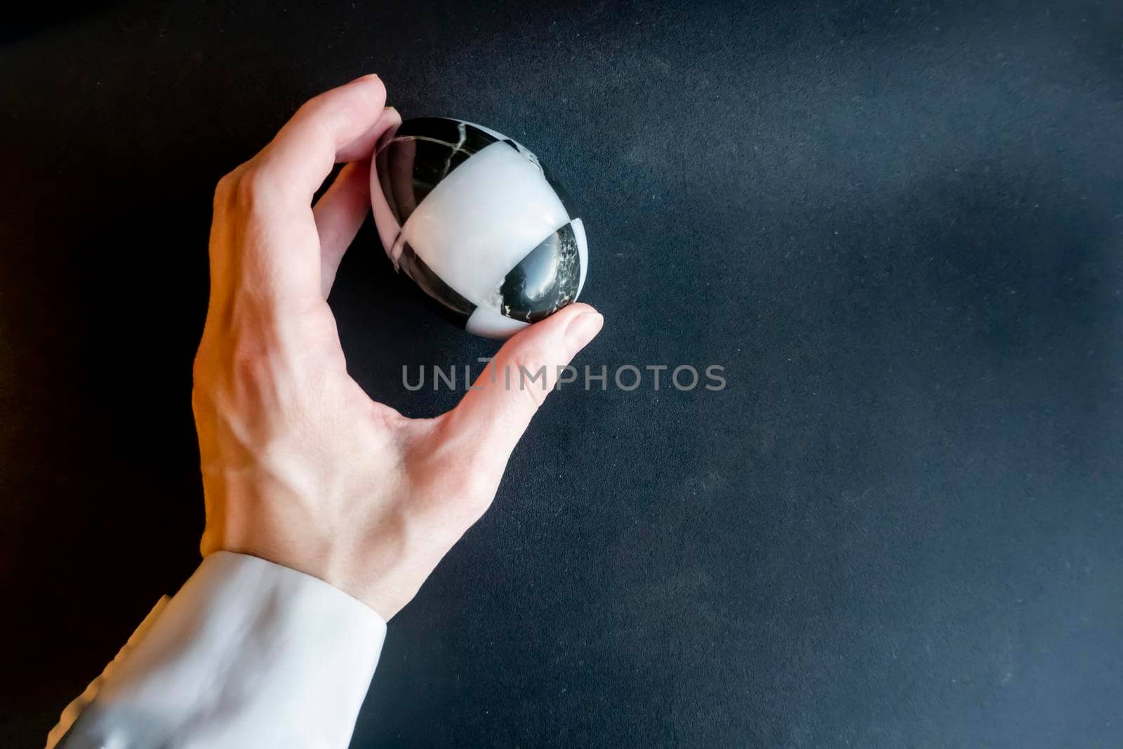 The hand holds a marble stone black and white egg on a black background. The concept of contrast. minimalism Easter theme. High quality photo