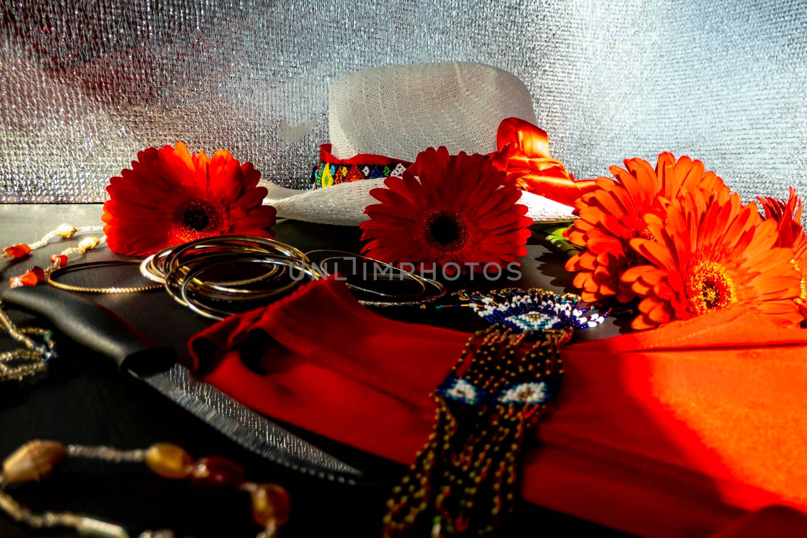 fashionable look from red and white accessories on a black background. Scarlet dress and white hat with a ribbon, jewelry made of beads and small stones, light jingling bracelets