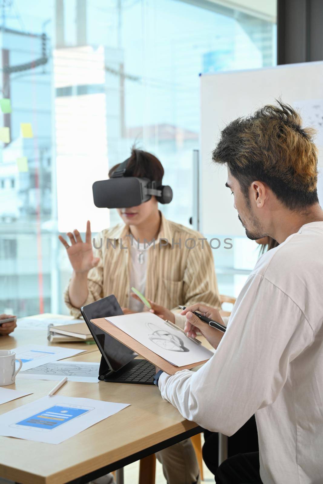 Website development team testing virtual reality headset, brainstorming on augmented reality improvement, future technology for business by prathanchorruangsak