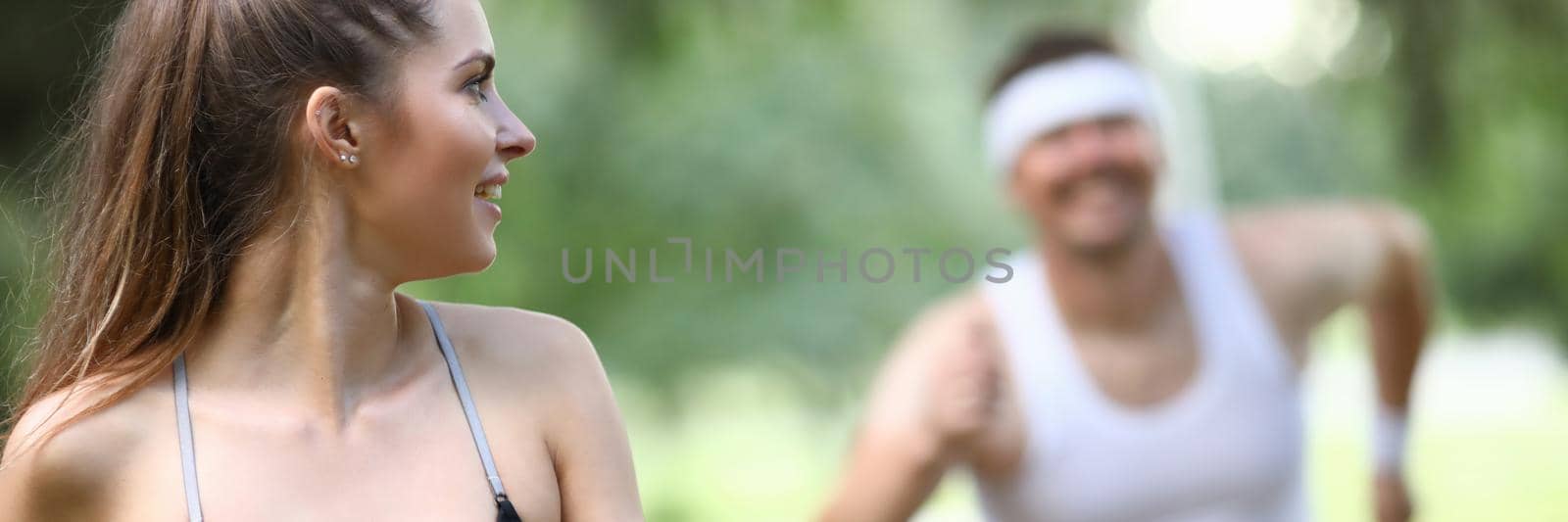 Man catching up with woman athlete in park. Outdoor sports concept