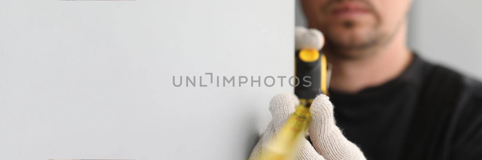 Male construction worker measuring size of wall with ruler closeup. Renovation and construction site concept