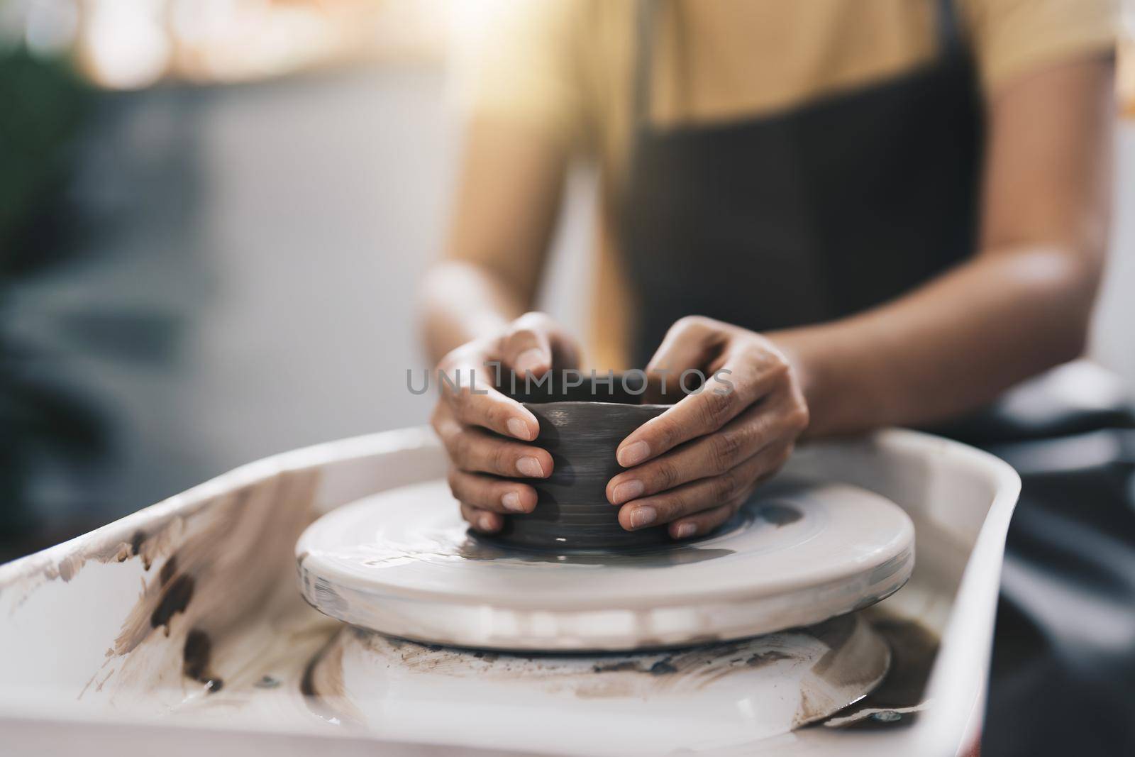 Craftsman hands making pottery bowl. Woman working on potter wheel. Family business shop sculpts pot from clay