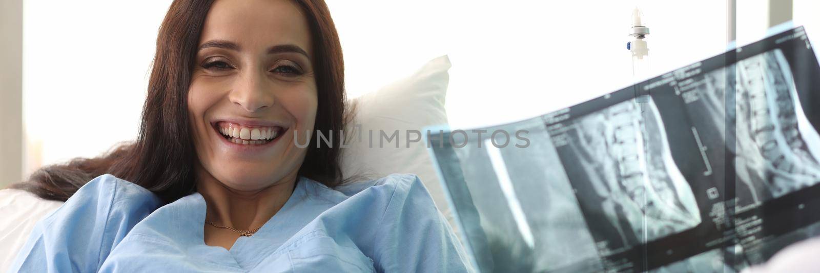 Doctor holding xray of spine in front of smiling female patient. Modern medicine and recovery concept