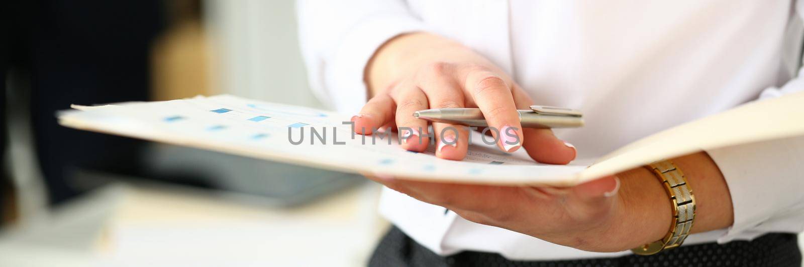 Female hands holding folder with documents in office closeup. Business administration concept