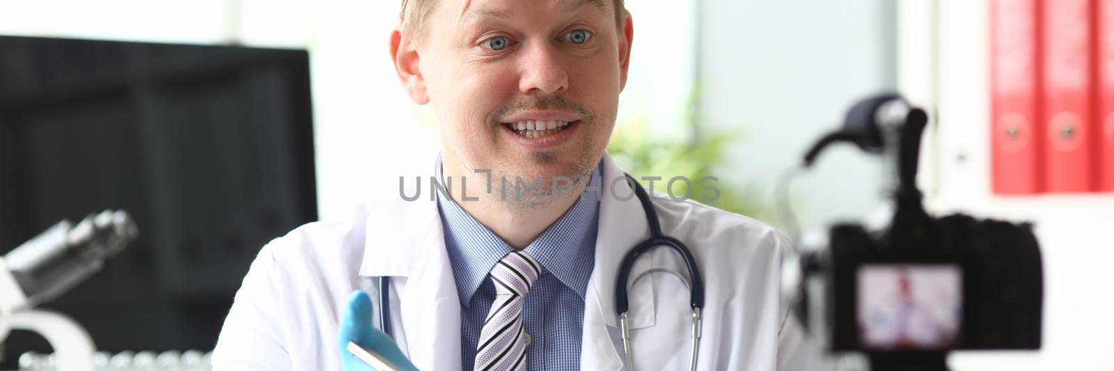 Male doctor speaking into camera in clinic. Medical blogging concept