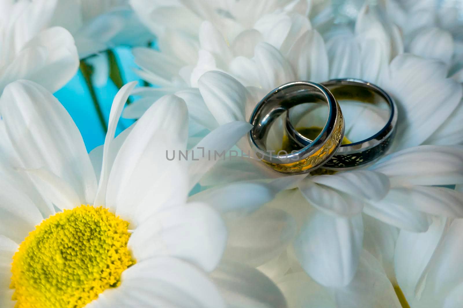 Wedding rings, jewelry and symbols attributes taken with selective focus. Holiday, celebration. Macro. Blur. Bridal bouquet on background. High quality photo