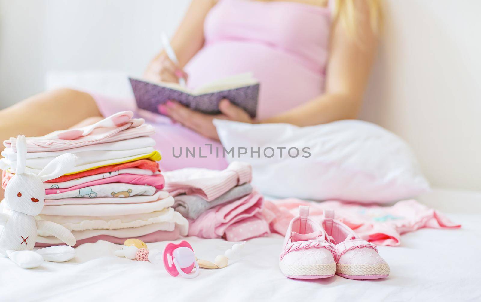 A pregnant woman is writing a list. Selective focus. people.