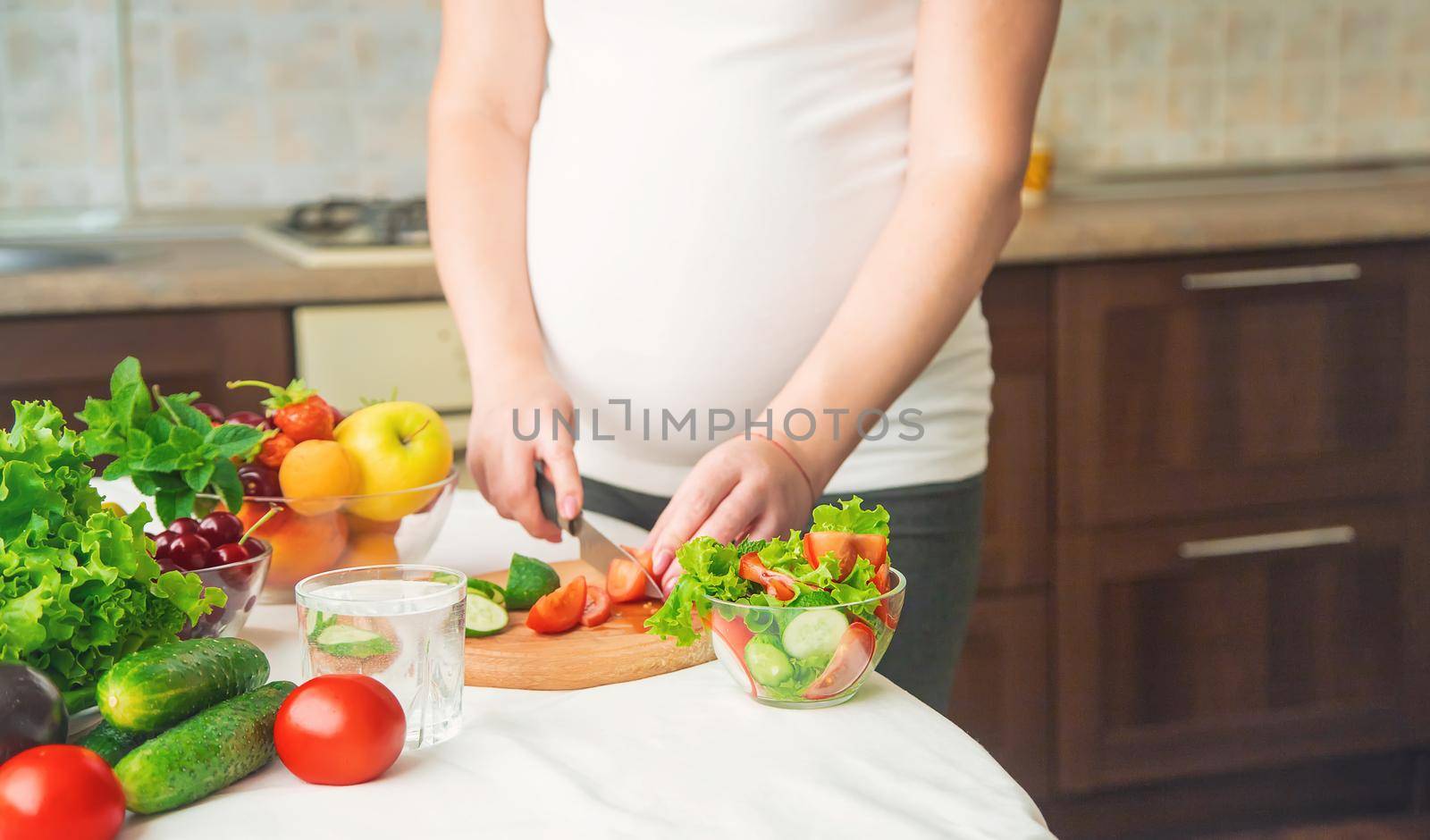 A pregnant woman eats vegetables and fruits. Selective focus. Food.