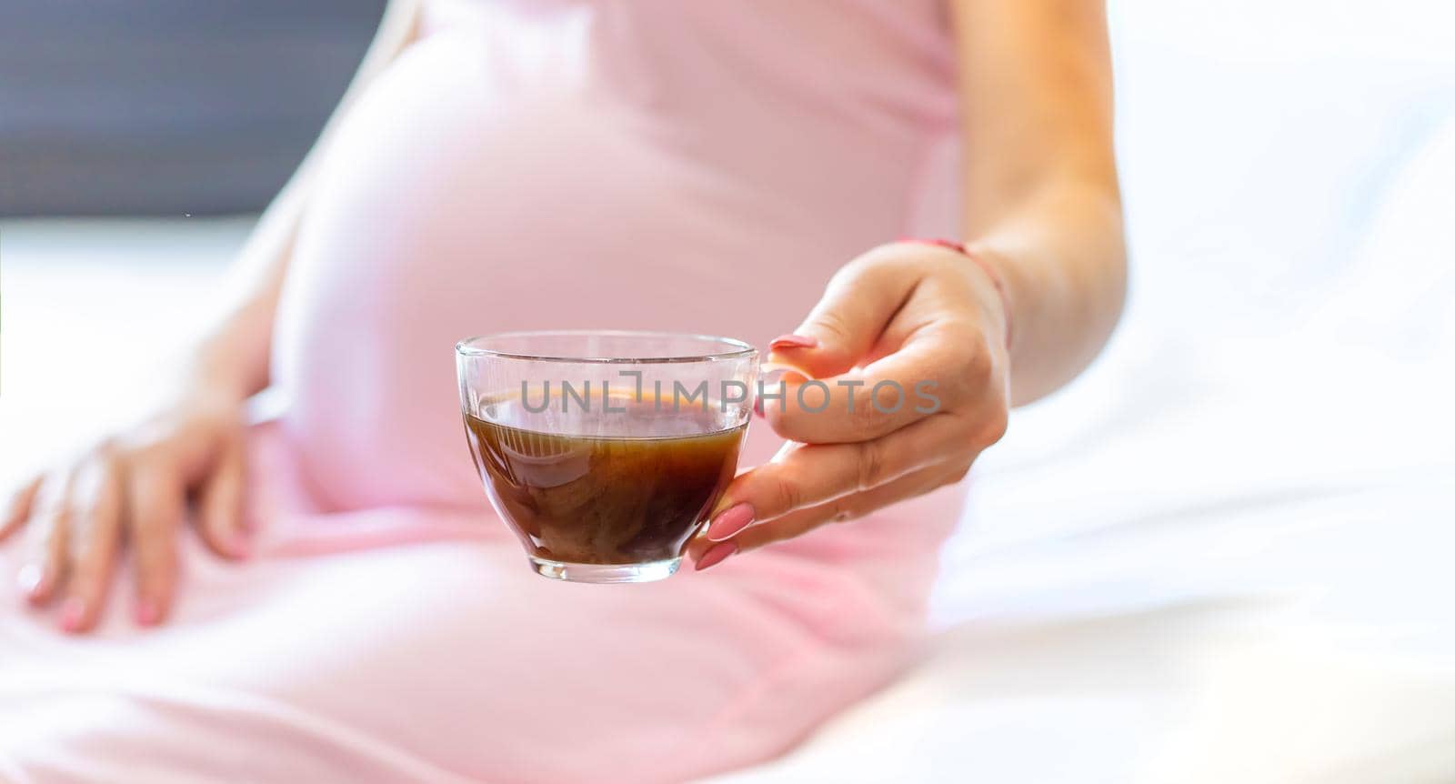 A pregnant woman is drinking coffee. Selective focus. people.