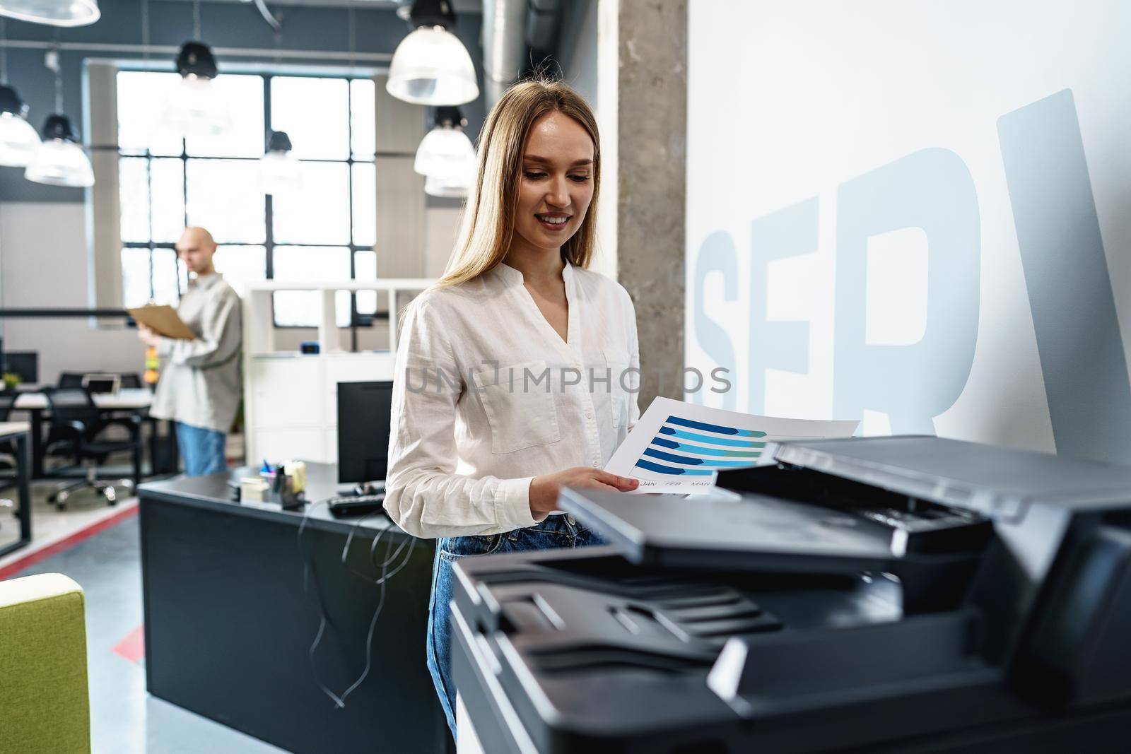 Young employee using modern printer in office, close up