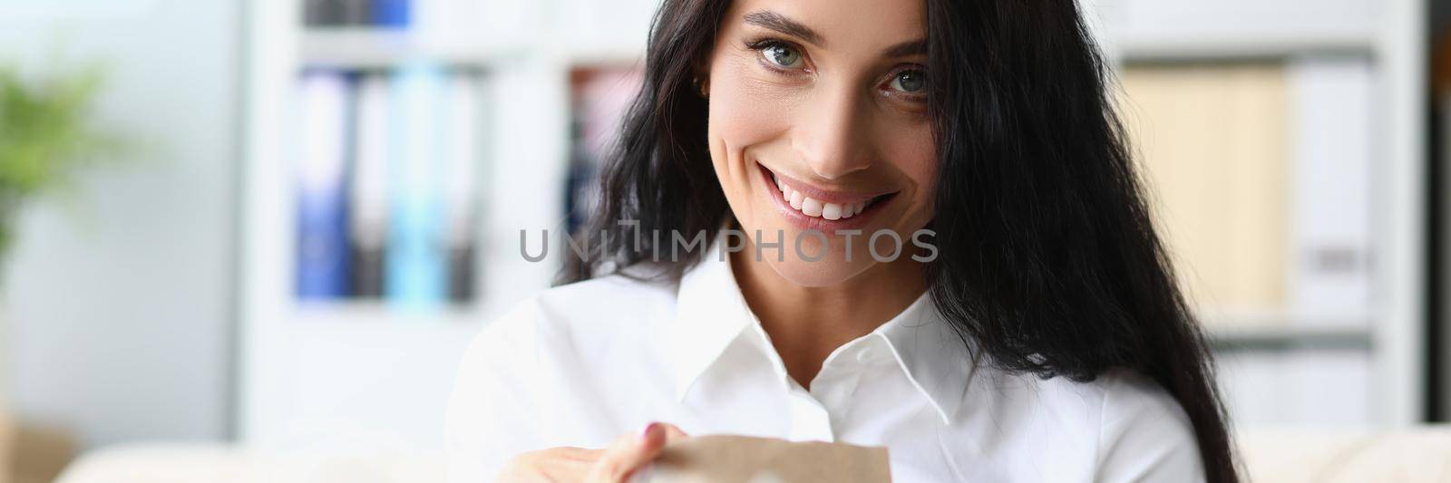 Smiling woman unpacking paper shopping bag at home. Buying gifts concept