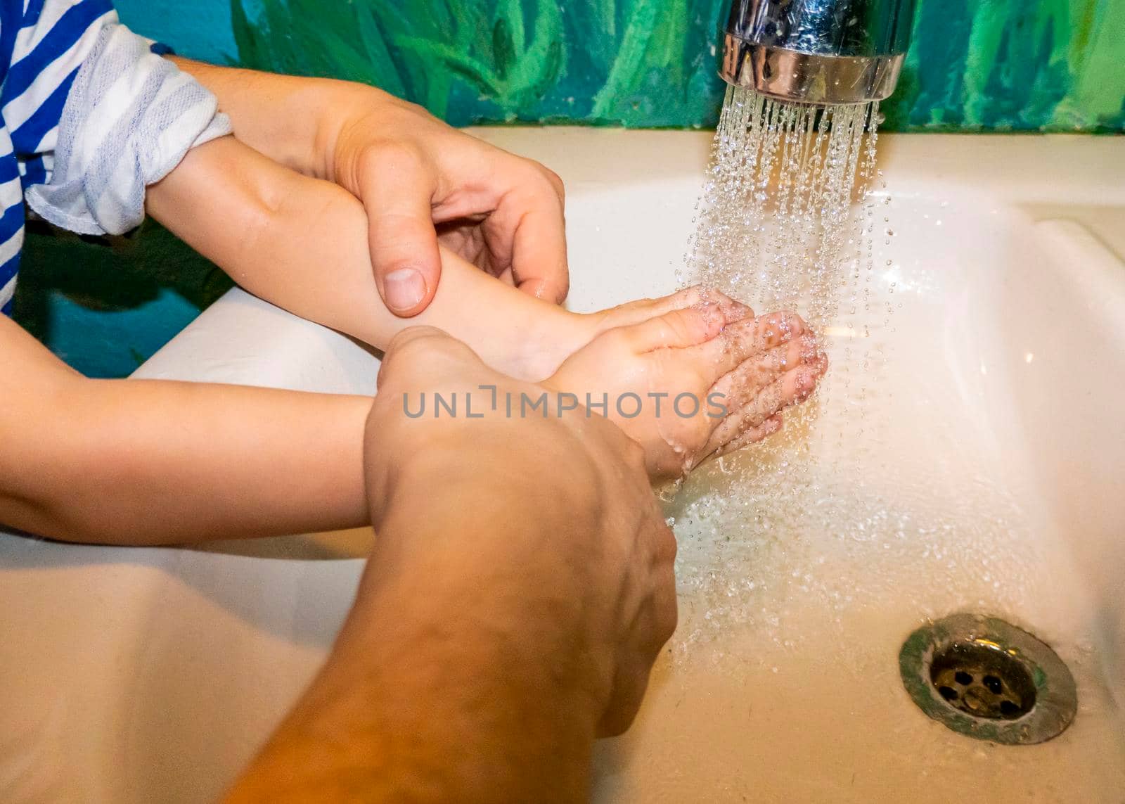 Close up of caucasian man and child together washes his hands in the bathroom. COVID - 19 prevention. water jet games, care. High quality photo
