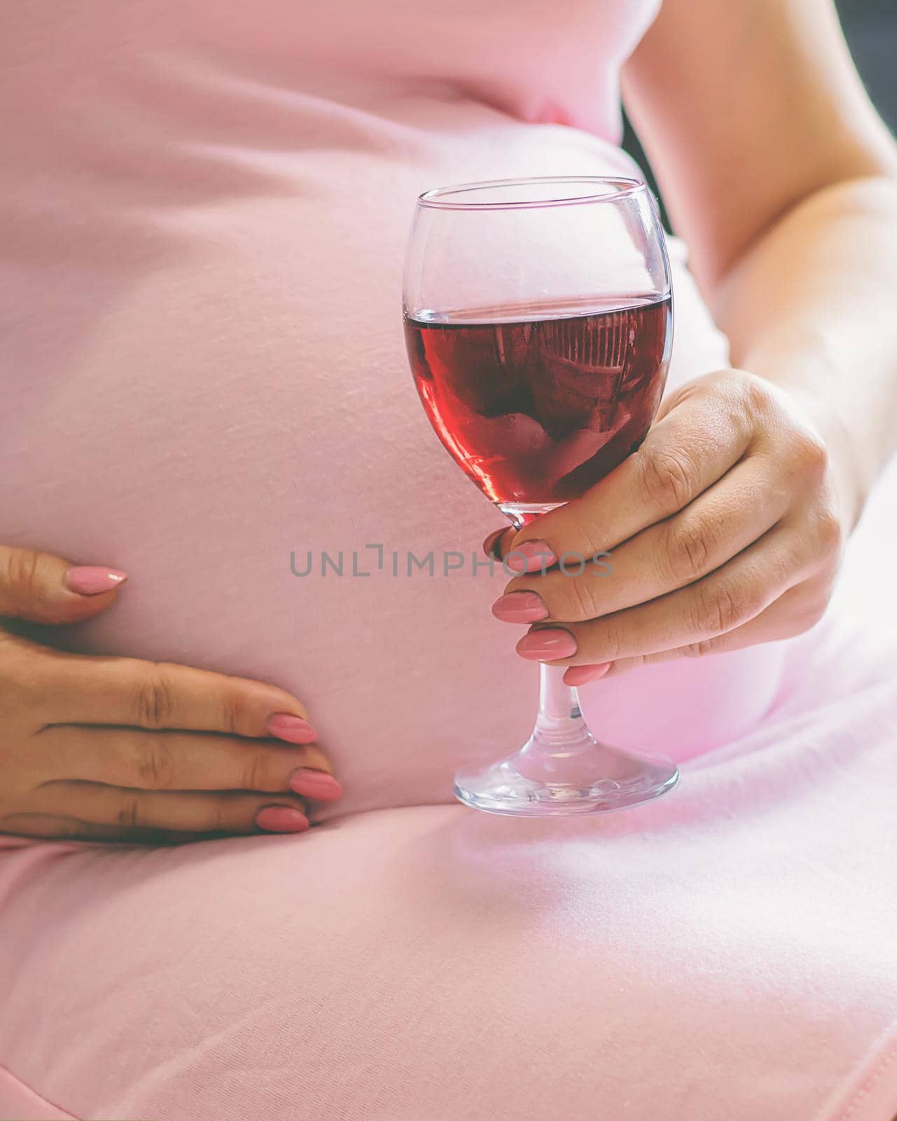 A pregnant woman is drinking wine. Selective focus. people.