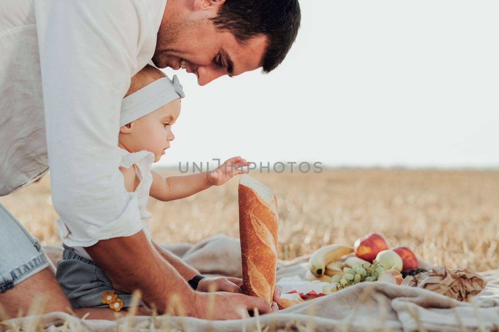 Side View of Father Playing With His Toddler Daughter, Dad with Child Having Picnic Outdoors in Field