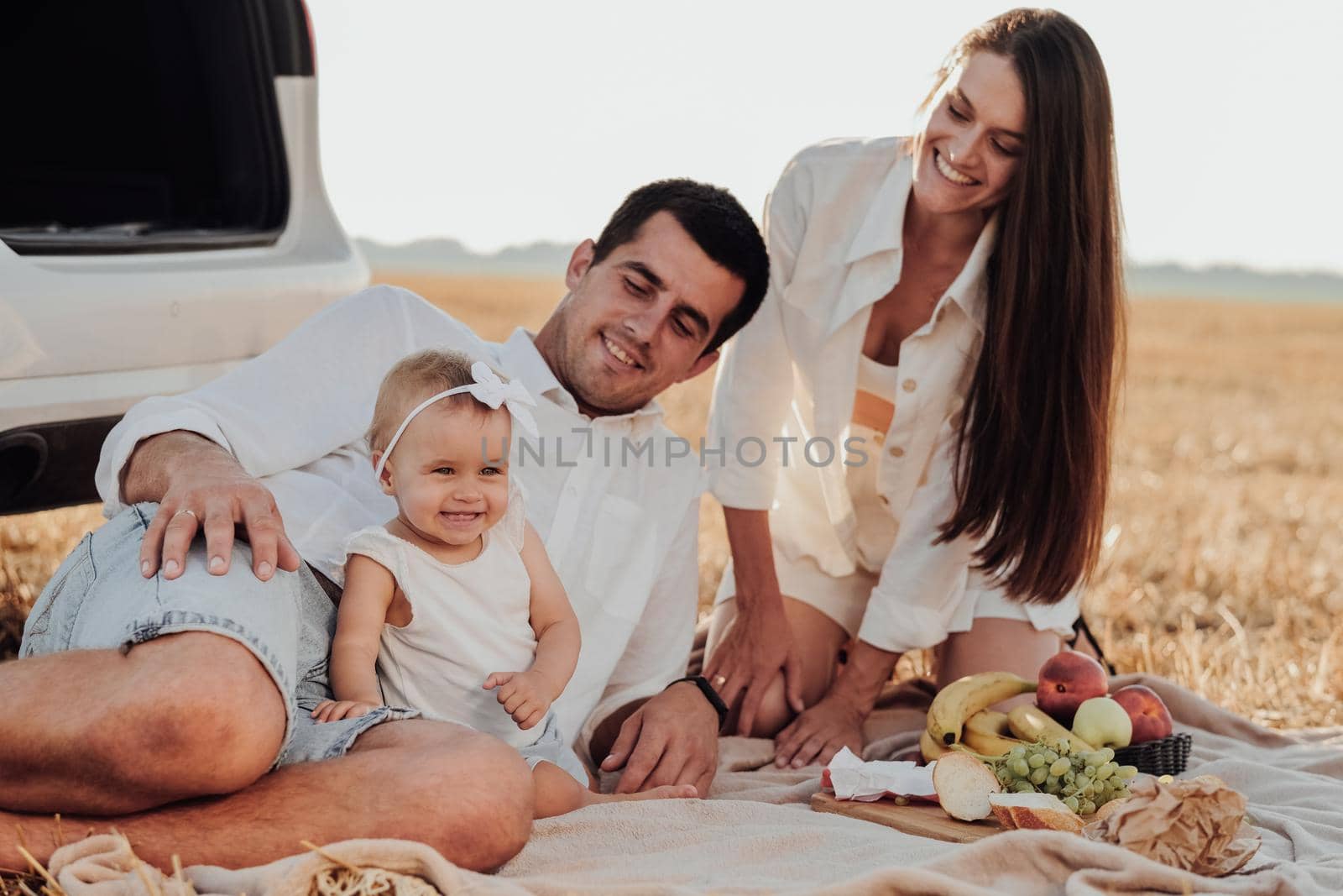 Close Up Portrait of Young Family, Mother and Father with Their Toddler Daughter Having Picnic Time Outdoors During Their Road Trip with Car