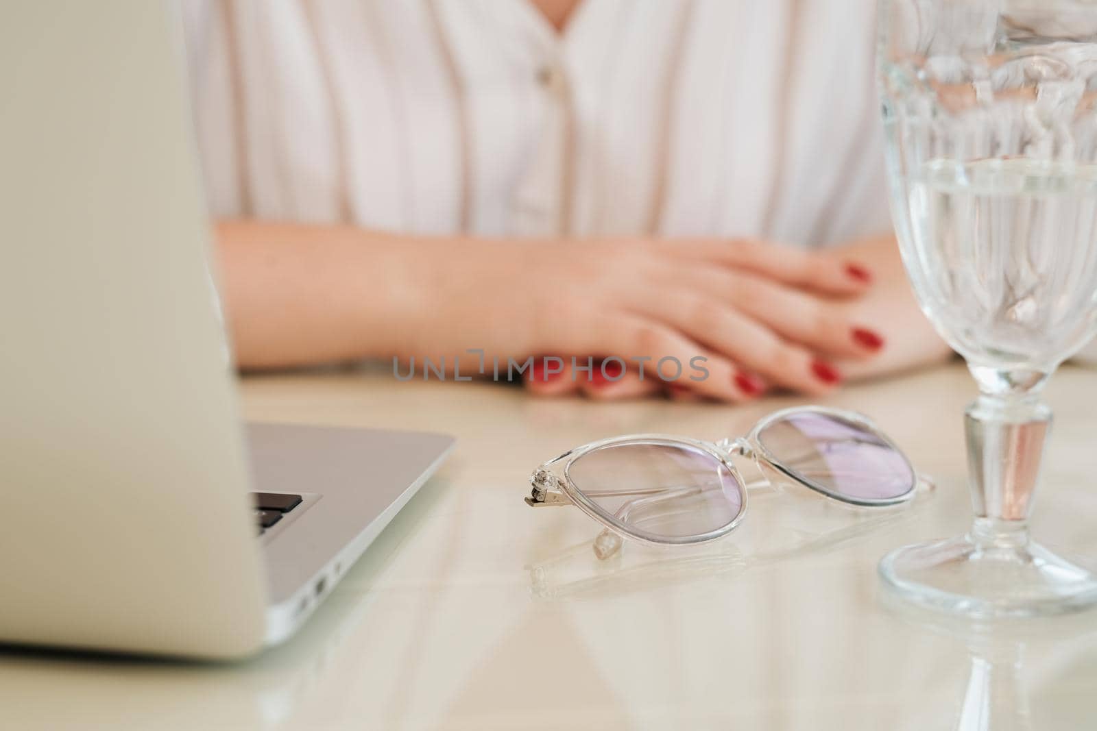 Close Up of Unrecognisable Woman Sitting by Table with Laptop, Glass of Water and Glasses, Freelance Concept