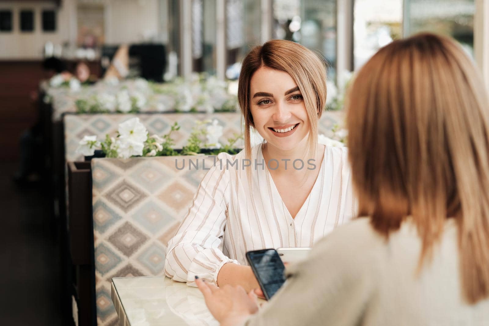 Cheerful Young Woman Having Lunch Meeting with Her Female Friend in Restaurant