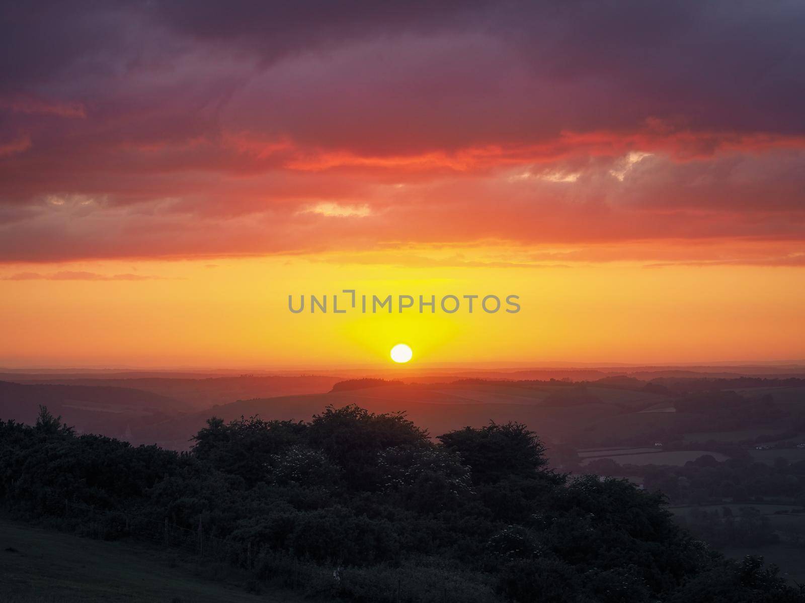 Stunning orange sunset looking out from Butser Hill, the highest point on the chalk ridge of the South Downs, Hampshire, UK