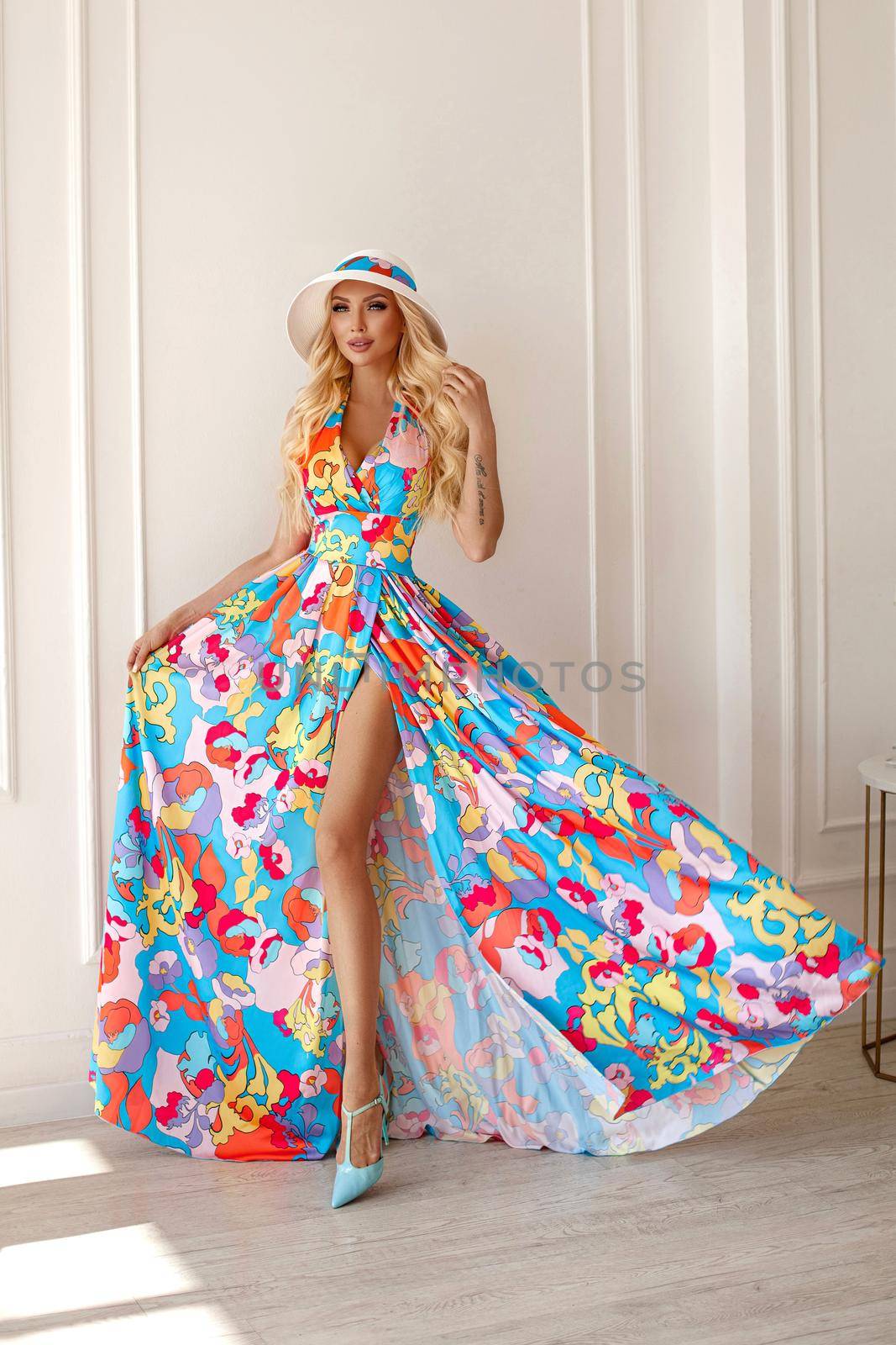 A beautiful sweet blonde woman in a bright outfit, a long skirt with a flower print, wavy hair,studio