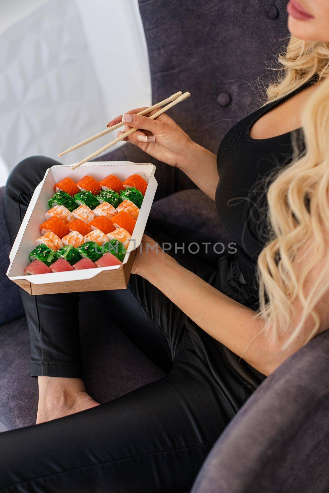 Eating sushi with chopsticks close up, food takeout and delivery service, salmon sushi rolls, tasty meal, sushi delivery. by StudioLucky