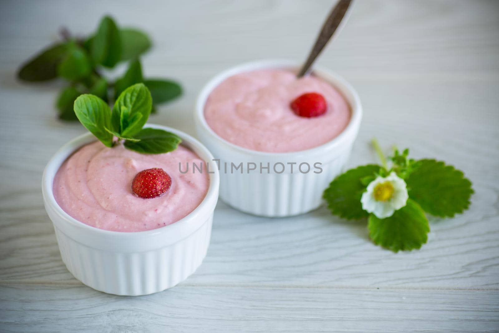 sweet curd mass whipped with fresh strawberries in a bowl, on a wooden table.