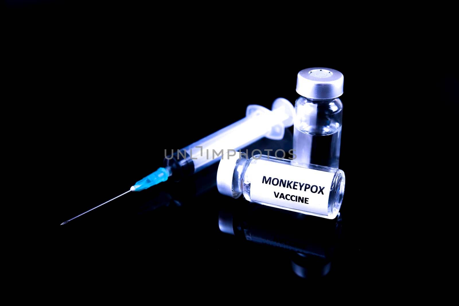 Close up picture of syringe and vials filled with Monkeypox vaccine on black background.