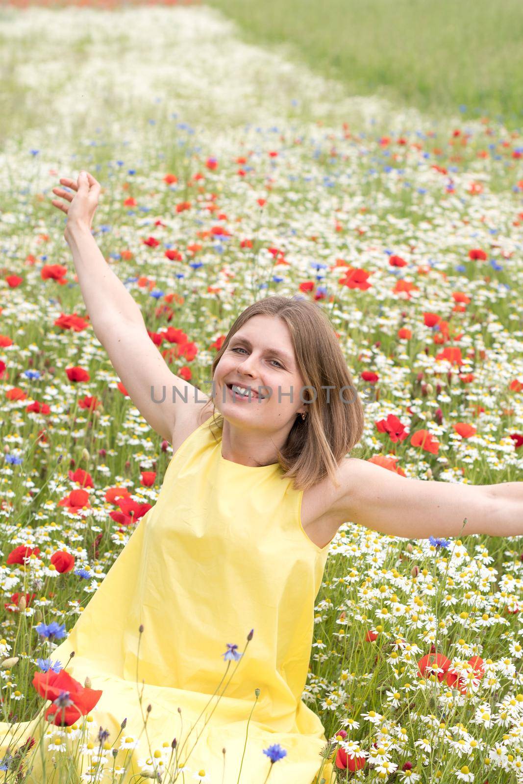 a beautiful young blonde woman in a yellow dress stands among a flowering field by KaterinaDalemans