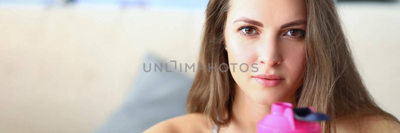 Portrait of woman athlete with pink plastic water bottle. Healthy lifestyle concept