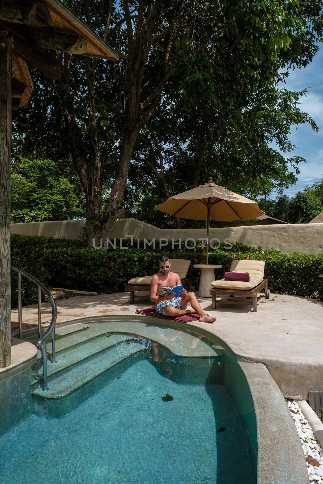 European man at infinity pool in Thailand looking out over the ocean, luxury vacation in Thailand, private pool villa. High quality photo