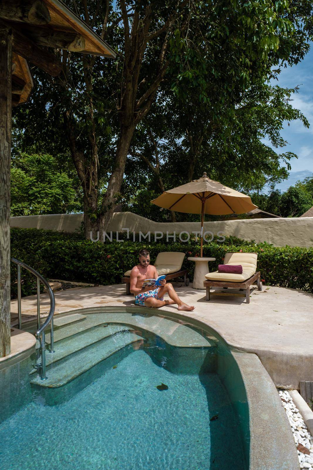 European man at infinity pool in Thailand looking out over the ocean, luxury vacation in Thailand, private pool villa by fokkebok