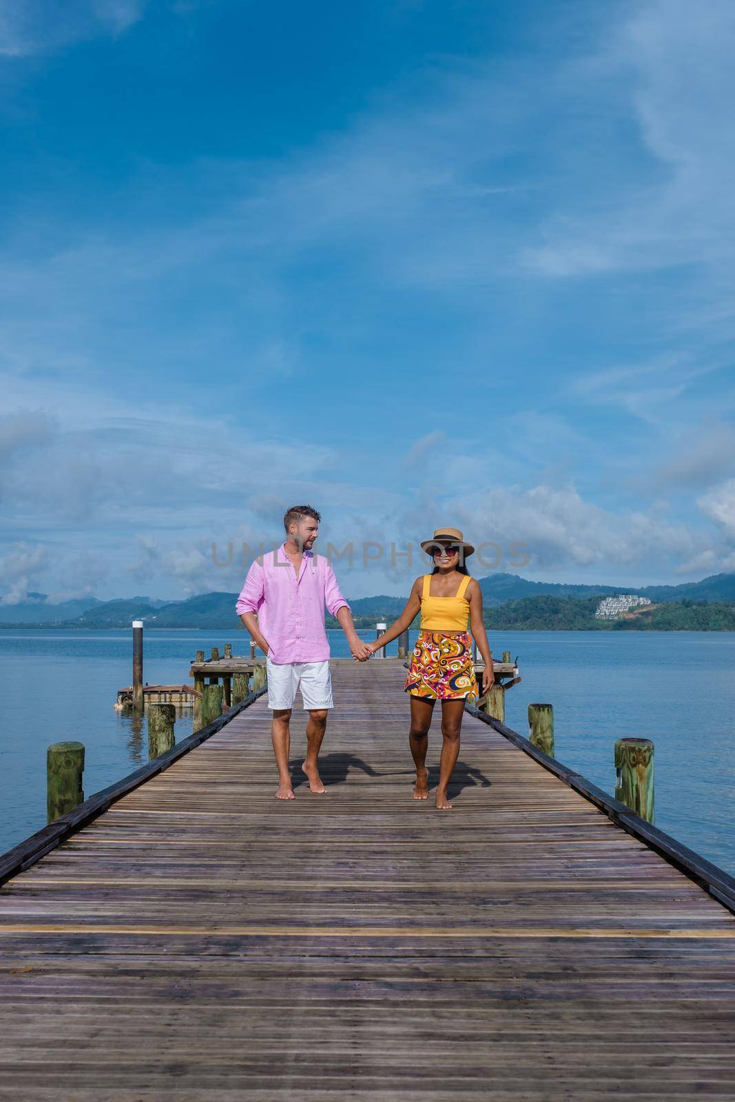 couple men and woman on a tropical island with wooden pier jetty in Thailand Phuket Naka Island