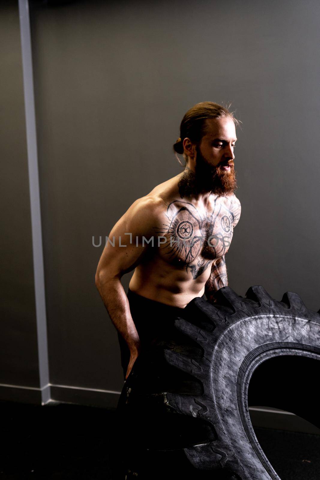 Fitness muscular gym tire wheel flipping male man ABS exercise, concept training weight from fit from huge concentration, effort health. Athletic muscle build, by 89167702191