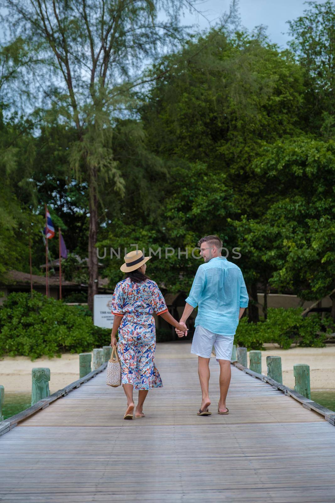couple men and woman on a tropical island with wooden pier jetty in Thailand Phuket Naka Island