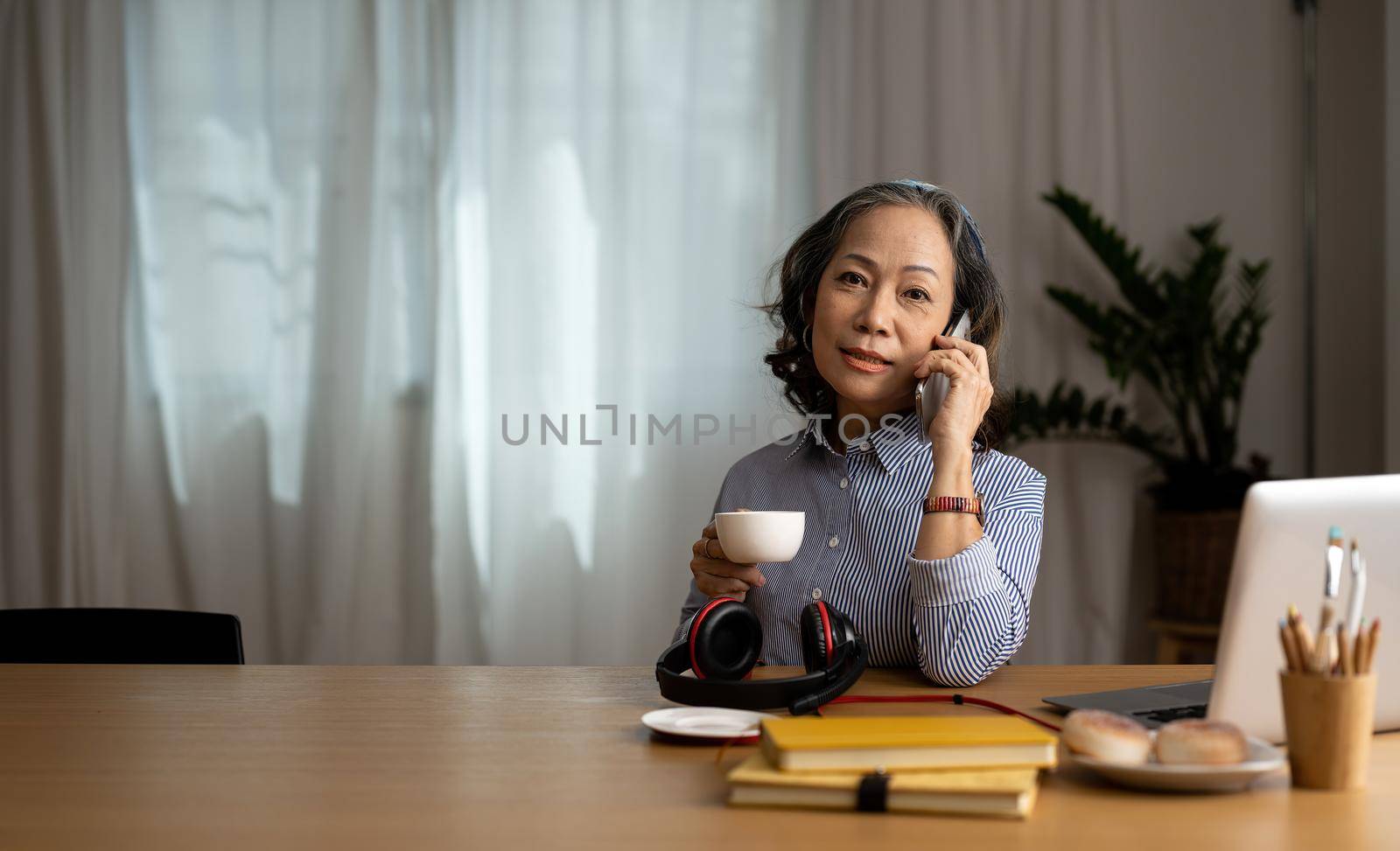 senior asian woman talk on cellphone discussing report using laptop computer. consultant advisor concept