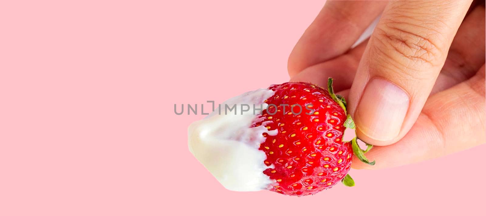 banner with female hand holds a strawberry with cream. juicy, sweet, ripe, red strawberries on a pink background. isolate