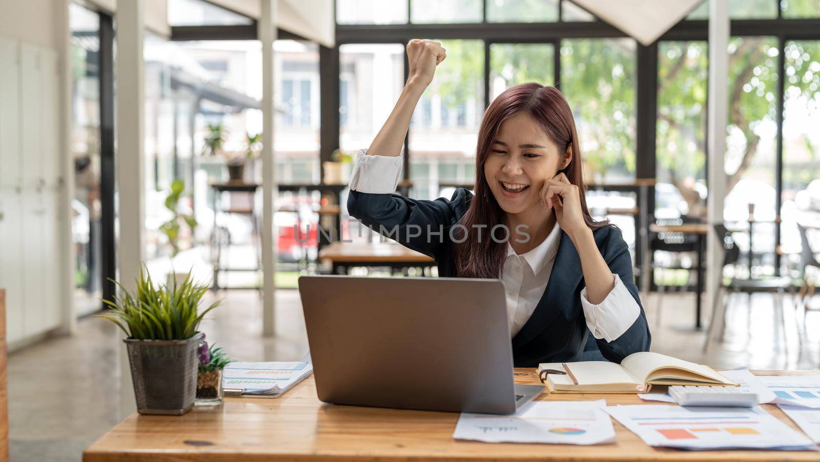 Portrait of happy young business asian woman celebrating success with arms up. positive expression, success in business concept.