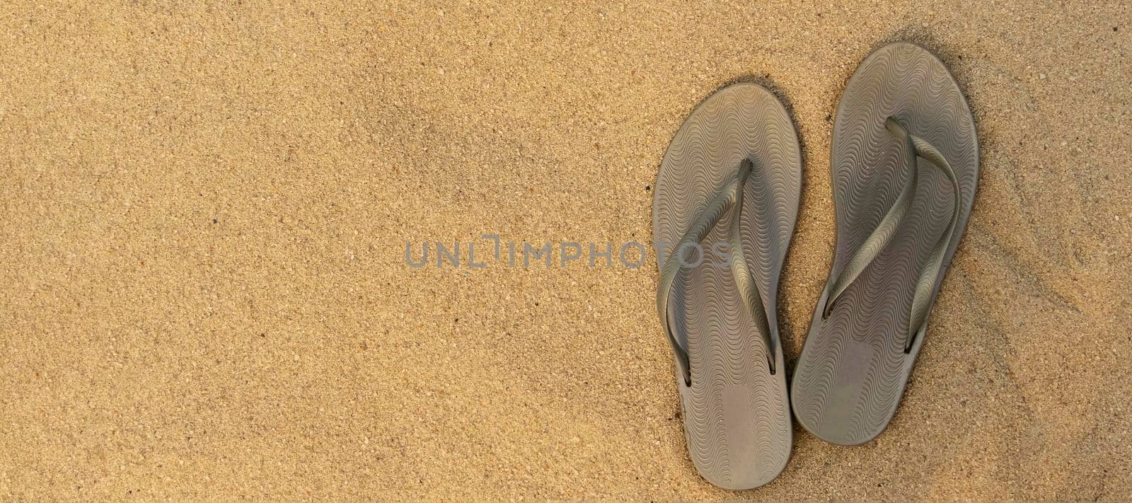 banner with light sandal or flip flops on the beach. golden sand. place for your text. top view. flat lay. concept of summer and vacation at sea