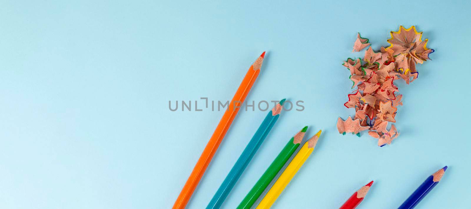 banner with Sharpened colored pencils and pencil shavings on pastel blue color. Rainbow or LGBT pencils. by Leoschka