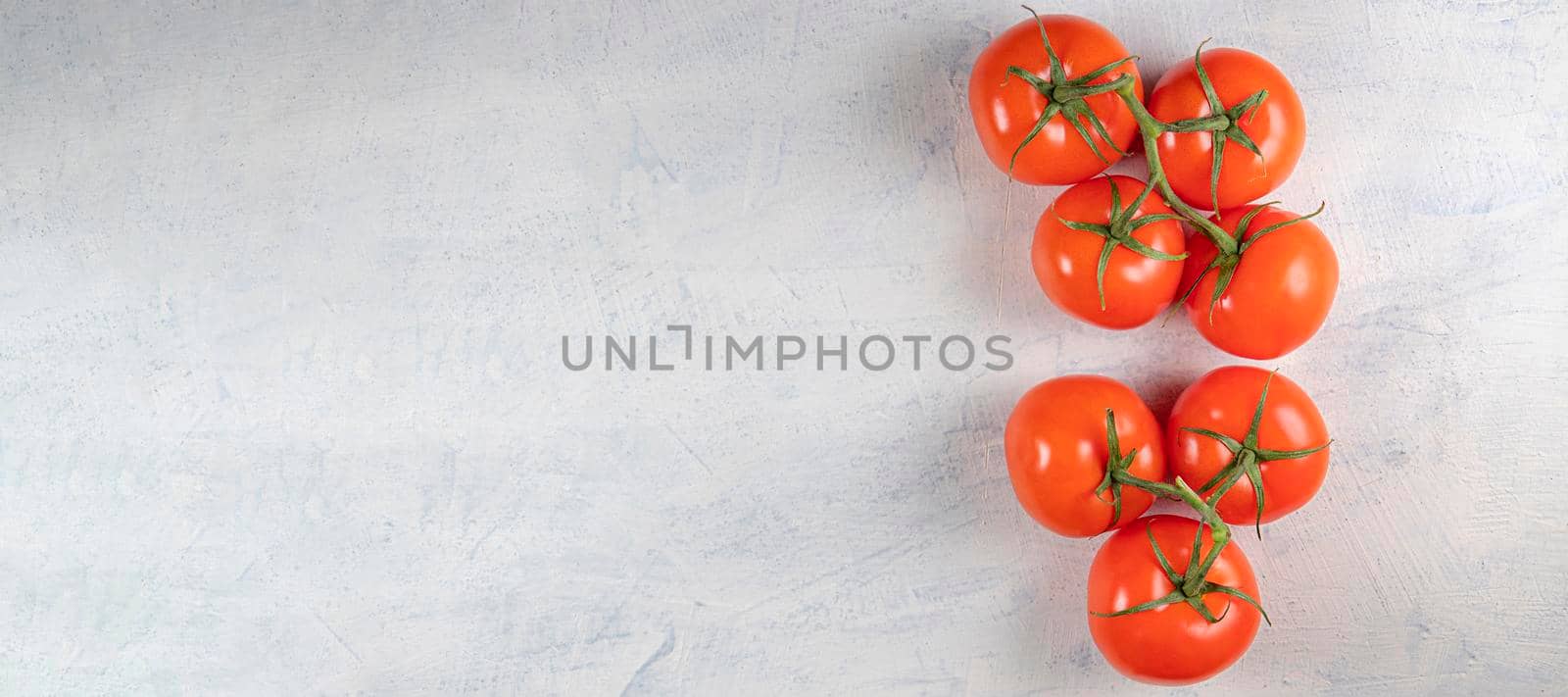 banner with seven red fresh and tasty tomatoes on a green twig on a white stone background. Top view. by Leoschka