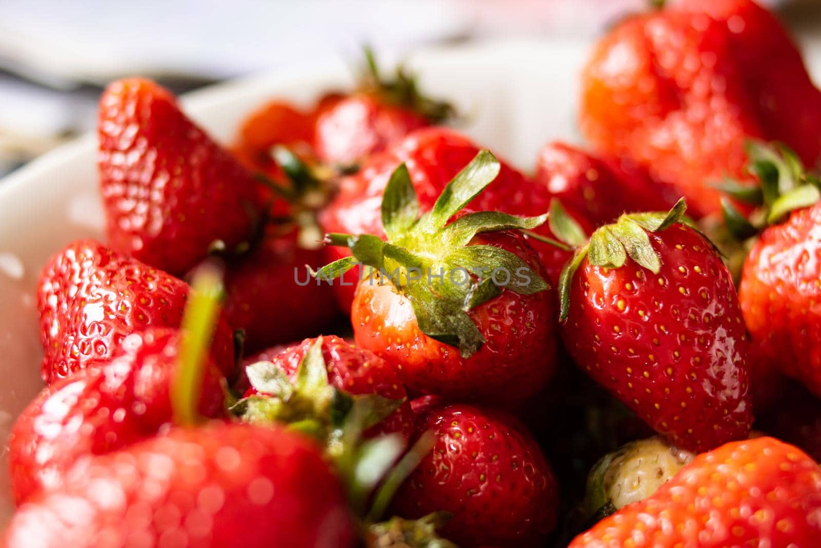 Heap of ripe red strawberries with green leaves close up